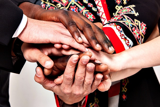 6 hands come together in a pile to represent teamwork