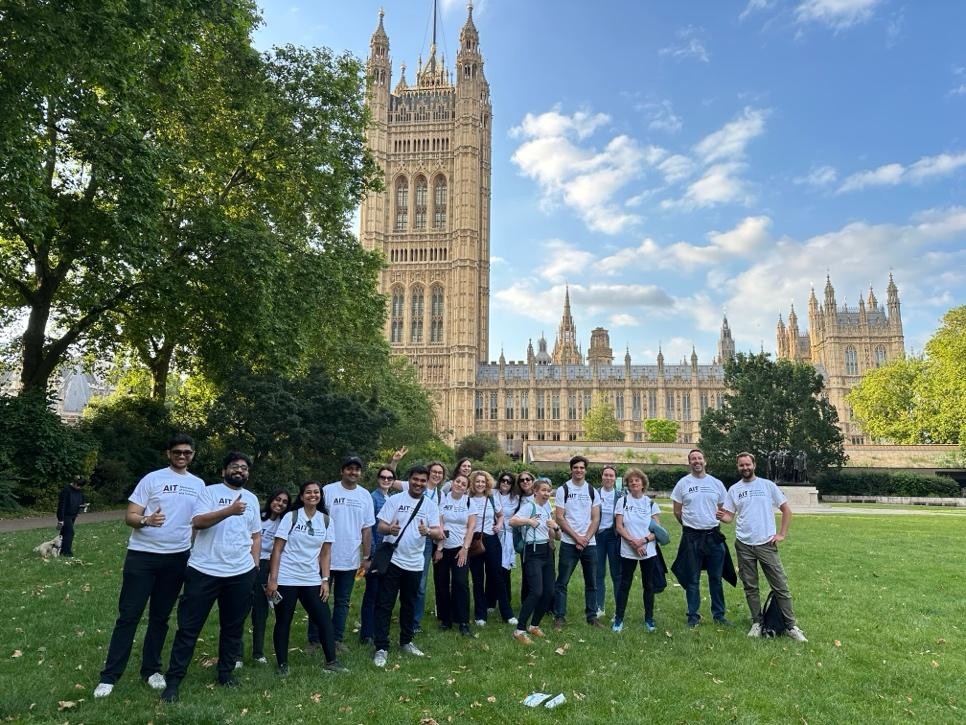 A group of people on a green lawn with an ornate building behind them