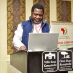 a man standing behind a laptop at a lectern