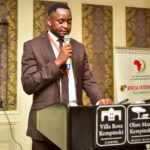 a man standing with a microphone at a lectern