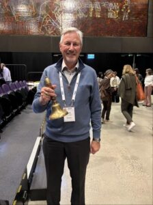 a man with a lanyard holding a bell