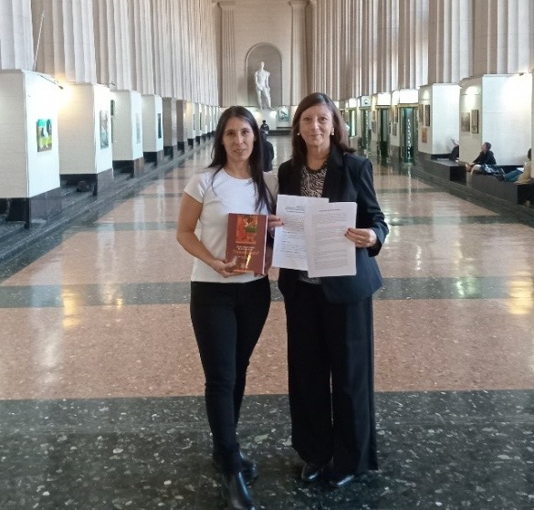 two graduates holding their qualifications